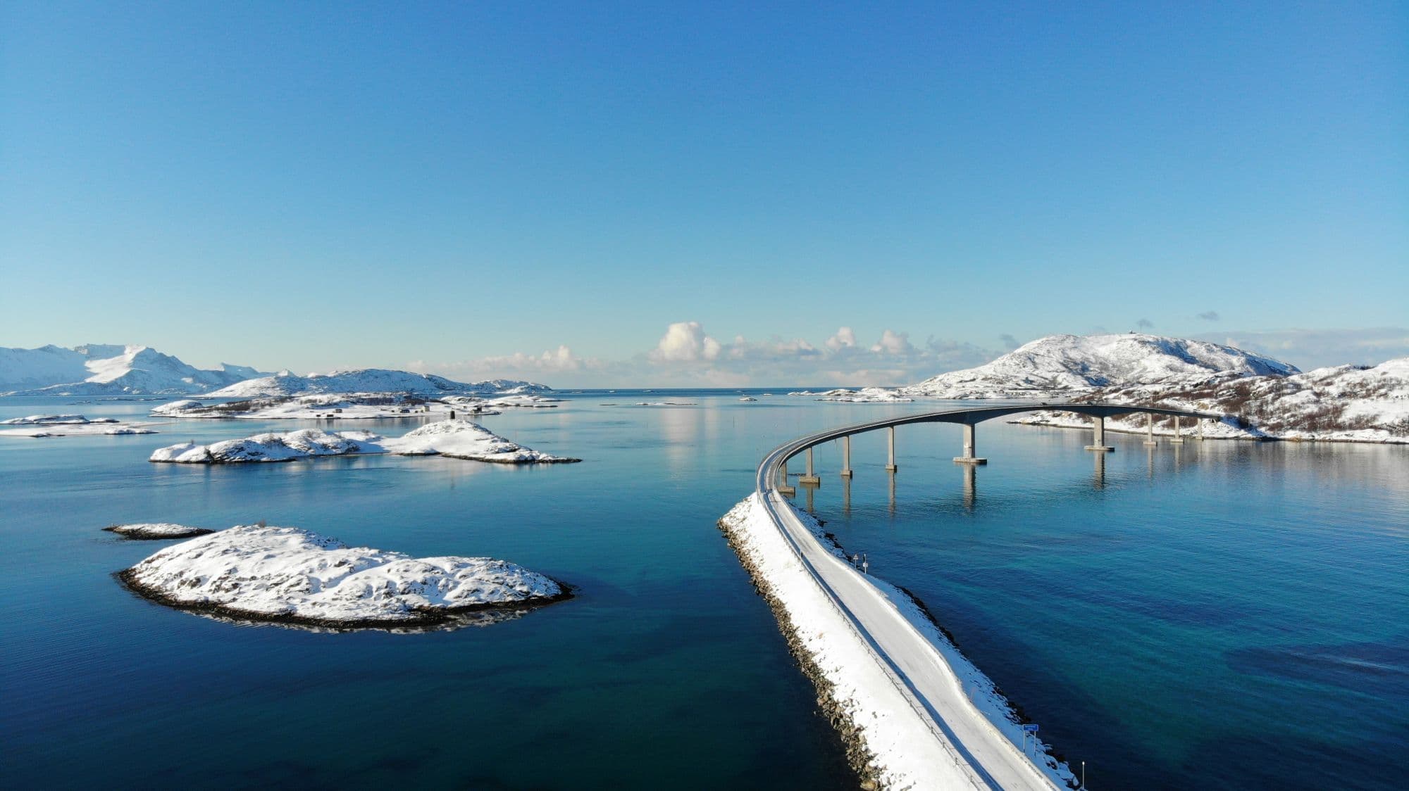 Arctic coastal landscape in Tromsø with snow-capped mountains, clear fjord waters and scattered islands